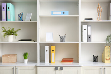 Sticker - White shelving unit with different stationery and houseplants in office