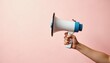 © umut hasanoglu - A hand holding a megaphone against a pink background, conveying a message or announcement.