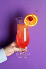 Wall Mural - Woman with glass of refreshing cocktail on purple background, closeup