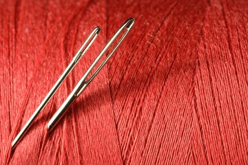 Wall Mural - Spool of red sewing thread with needles, macro view