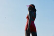 © SHOTPRIME STUDIO - A confident woman in a red athletic outfit stands against a clear blue sky, showcasing strength and determination