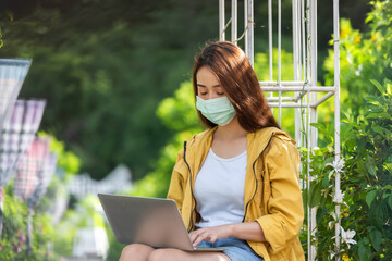 Lifestyle person Girl enjoy listening music and play laptop on the grass field of the nature park in the morning . Concept lifestyle