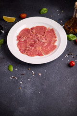 Wall Mural - tuna carpaccio - slices of fresh raw tuna fillet on white ceramic plate