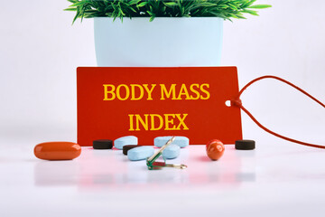 Wall Mural - Medical concept. The inscription BODY MASS INDEX on a red card, with pills, vitamins in the foreground on a white background