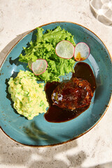 Wall Mural - Gourmet Beef Cheek with Mashed Potatoes and Fresh Green Salad on Blue Plate