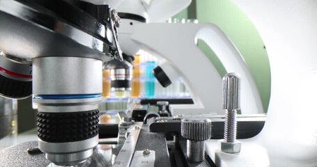 Wall Mural - Closeup of microscope lens in laboratory and test tube with liquid