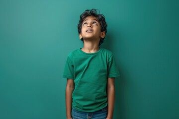 Wall Mural - A young boy wearing a green shirt is looking up at the ceiling