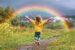 © siripimon2525 - A child jumps in front of a rainbow, making it look like they are holding the rainbow