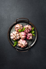 Wall Mural - Metal tray with fresh organic garlic. Top view. On a black background. Minimalist photo.