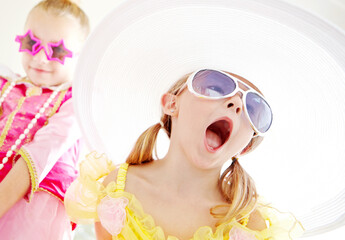 Fancy, friends and children dress up in home with fun, glamour and confidence with sunglasses for character play. Princess, costume and happy girl kids with smile, fantasy and creative development.