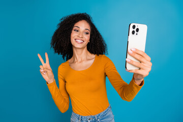 Canvas Print - Photo portrait of attractive young woman take selfie photo show v-sign dressed stylish yellow clothes isolated on blue color background