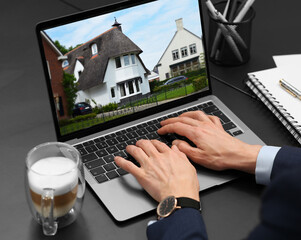 Wall Mural - Woman looking for house on real estate market website at table, closeup