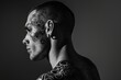 © Phuriphat - A man with tattoos and piercings stands in front of a gray background