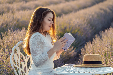 Canvas Print - A woman is sitting in a field reading a book. The scene is peaceful and serene, with the sun shining down on the woman and the surrounding flowers. The woman is enjoying her time alone.