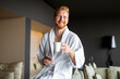 © NDABCREATIVITY - Handsome, muscular, young man drinking his morning coffee in a hotel room
