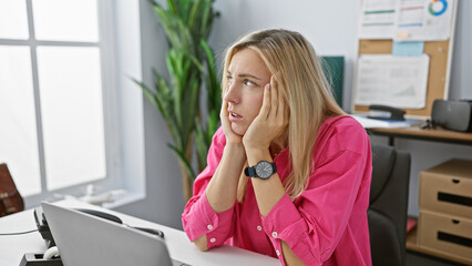 Sticker - A stressed young woman at her workplace showing frustration in an office environment with a computer.