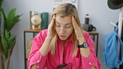 Sticker - A stressed young blonde woman wearing a pink shirt feeling headache at her cluttered office space