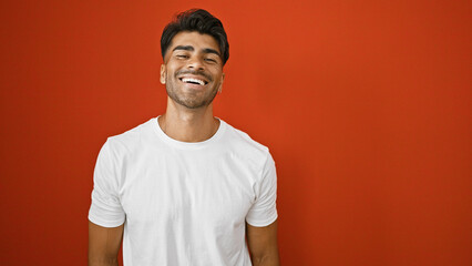 Hispanic man smiling in white shirt against red background