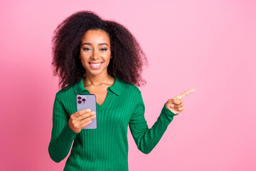 Wall Mural - Photo portrait of lovely young lady hold device point empty space dressed stylish green garment isolated on pink color background