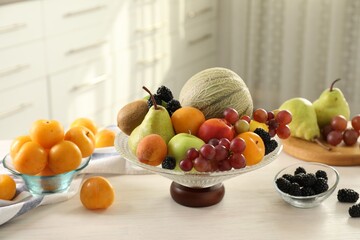 Wall Mural - Glass vase with different fruits and berries on white table indoors