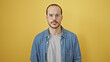 © Krakenimages.com - Portrait of a confident hispanic man with a beard, glasses and denim shirt against a yellow isolated background.