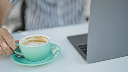 Sticker - Close-up of a caucasian male's hand holding a coffee cup on a terrace with a laptop in the background