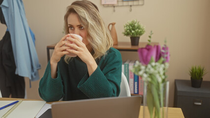 Sticker - A contemplative young woman sipping coffee in a cozy home office environment, showcasing a modern, casual lifestyle.