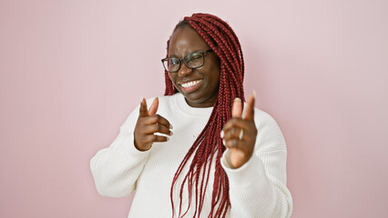 Poster - Smiling black woman with braids, glasses, and white sweater over a pink background pointing and winking at camera