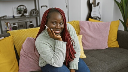 Poster - Beautiful african woman with braids smiling in a cozy living room interior