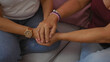 © Krakenimages.com - Women holding hands while sitting together in a living room, indicating support and friendship in a cozy home setting with mature adults.