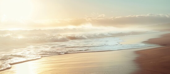Poster - Misty morning sun shining above a sandy ocean shore with waves providing a clear view in the distance for a copy space image