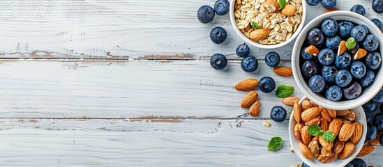 Aufkleber - Top view of a white wooden background with a breakfast oatmeal featuring blueberries and almonds providing copy space image
