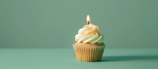 Aufkleber - A tasty cupcake with a lit candle is placed on a soft green backdrop leaving room for a message in this copy space image