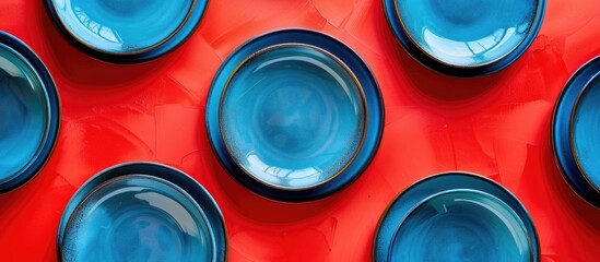 Wall Mural - Top view of a striking pattern of blue plates on a vibrant red backdrop with ample copy space image