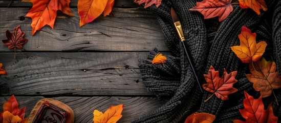 Sticker - Top view of a fall themed arrangement featuring autumn leaves a black scarf and a paintbrush on a wooden backdrop perfect for display with copy space in the image