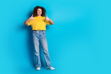 Wall Mural - Full length photo of lovely young lady thumb up approve dressed stylish striped yellow garment isolated on blue color background