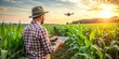 © Sirinporn - Agricultural technician holds a tablet displaying soil analysis data while standing in a lush green corn field, with a drone flying overhead in the background.