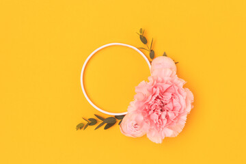 Wall Mural - Round frame made of pink rose, carnation flowers and green eucalyptus branches on a yellow background. Place for text.