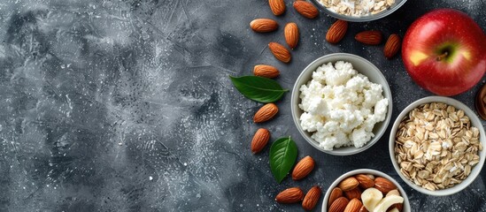 Wall Mural - Top view of wholesome breakfast ingredients like oatmeal, almonds, apple, and cottage cheese on a gray background with space for copied images. image with copy space