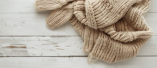 Wall Mural - Top down view of beige knitted scarf and mittens on a white wooden table with room for text in the image. Copy space image. Place for adding text and design