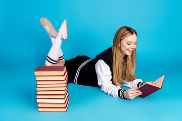 Poster - Photo of cute lovely pretty girl wear trendy clothes long socks lie floor read fiction story isolated on blue color background