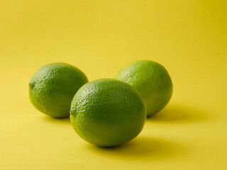 Lime, tropical citrus fruit on yellow background and copy space.