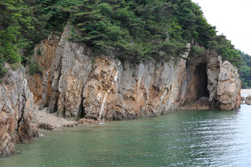 Wall Mural - Summer view of Yongcheon Cave and red cliff besides the sea at Janggohang-ri near Dangjin-si, South Korea