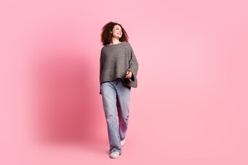 Wall Mural - Full length photo of lovely young lady walking look empty space dressed stylish gray garment isolated on pink color background