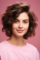 Woman with short hair and pink top smiling at camera.