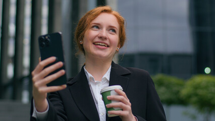 Happy smiling laughing gen z Caucasian girl woman female businesswoman blogger drinking coffee talking mobile phone video business call conversation webcam speak online connection outdoors city street