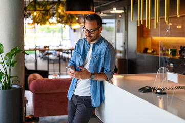 Wall Mural - serious young businessman checking social media applications over mobile phone by table in office