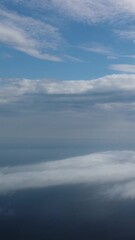 Wall Mural - aerial view. blue sky sun and fog over calm sea. the drone flies over foggy and fluffy clouds. abstr