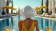© KeetaKawee - Elegant and stylish woman wearing a wide brimmed straw hat relaxing by the poolside of a luxurious tropical resort sipping a refreshing cocktail and soaking up the warm summer sun in a peaceful