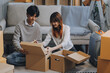 © ARMMY PICCA - Young Asian couple relocating to a new house, joyfully packing and unpacking belongings. Expertise in moving, packing, togetherness, and creating a new home together.